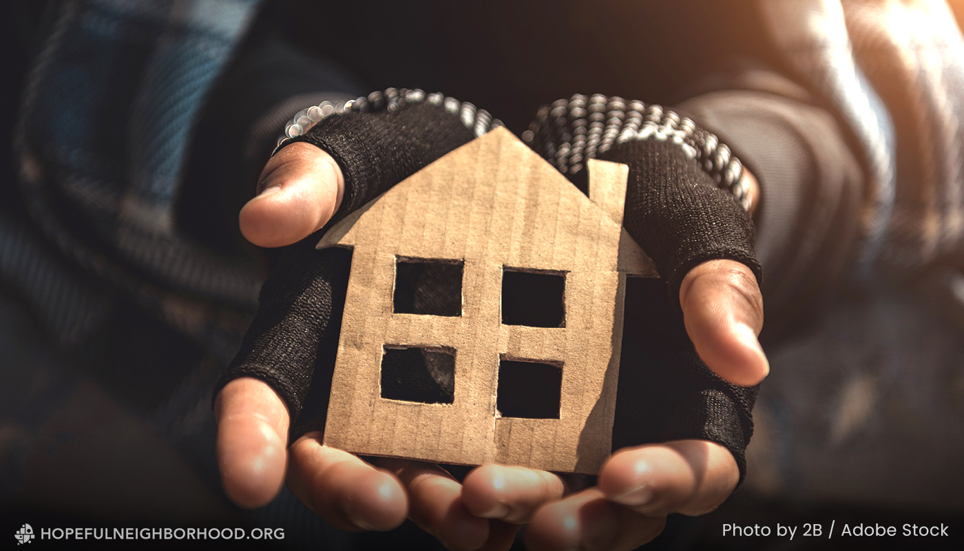 Hands holding a cutout of a house from a cardboard box.