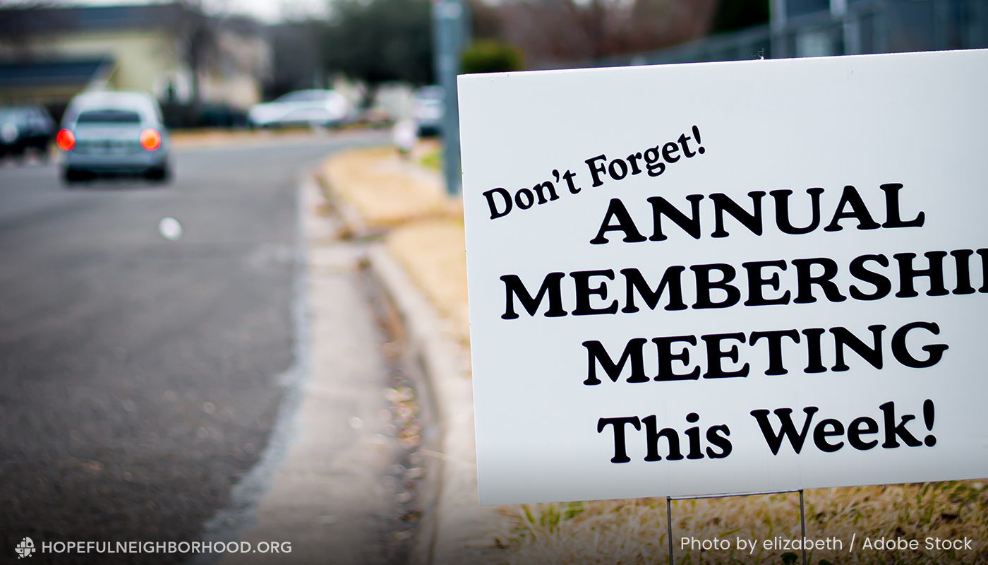 Photo of a suburban road with a sign along the side that says, "Don't Forget! Annual Membership Meeting This Week!"