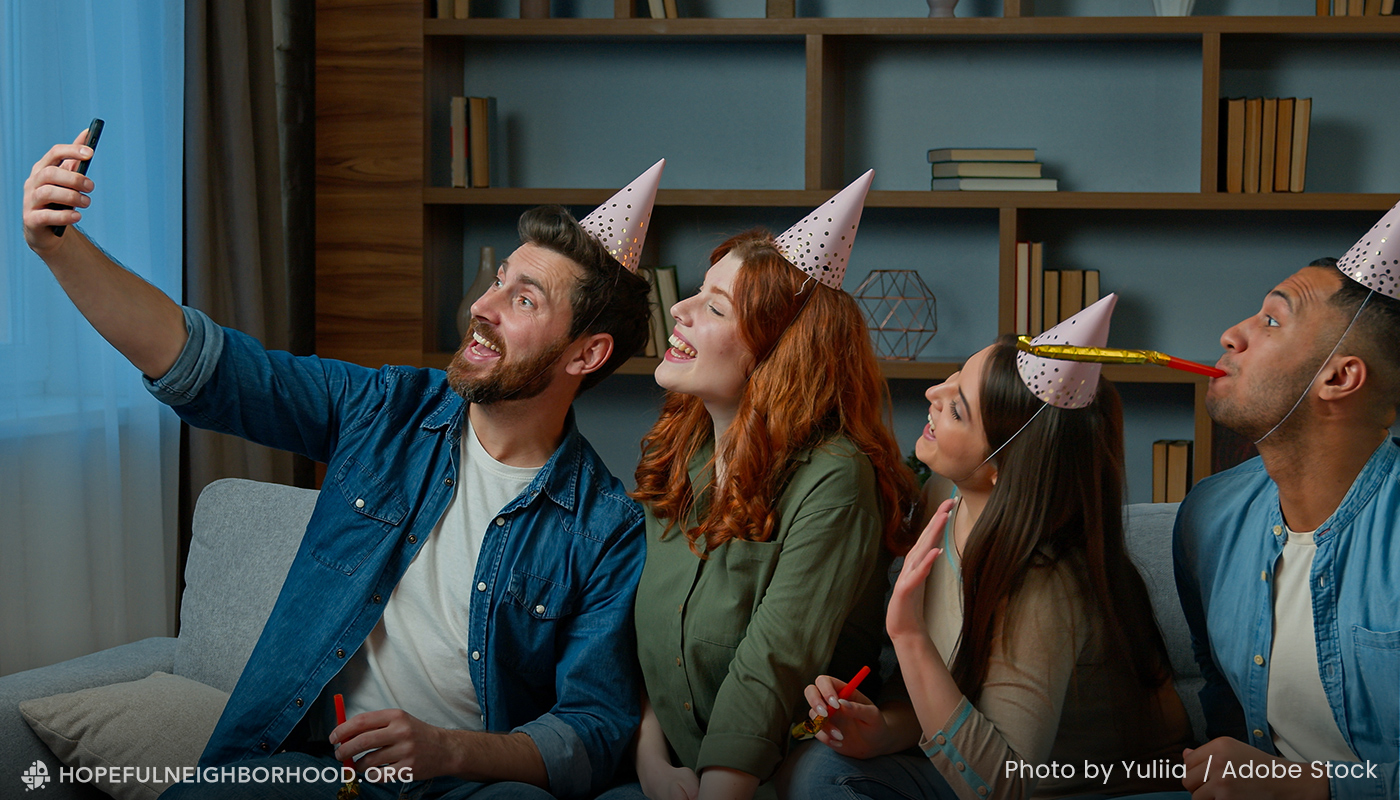 A group of young adult friends take a selfie while wearing party hats.